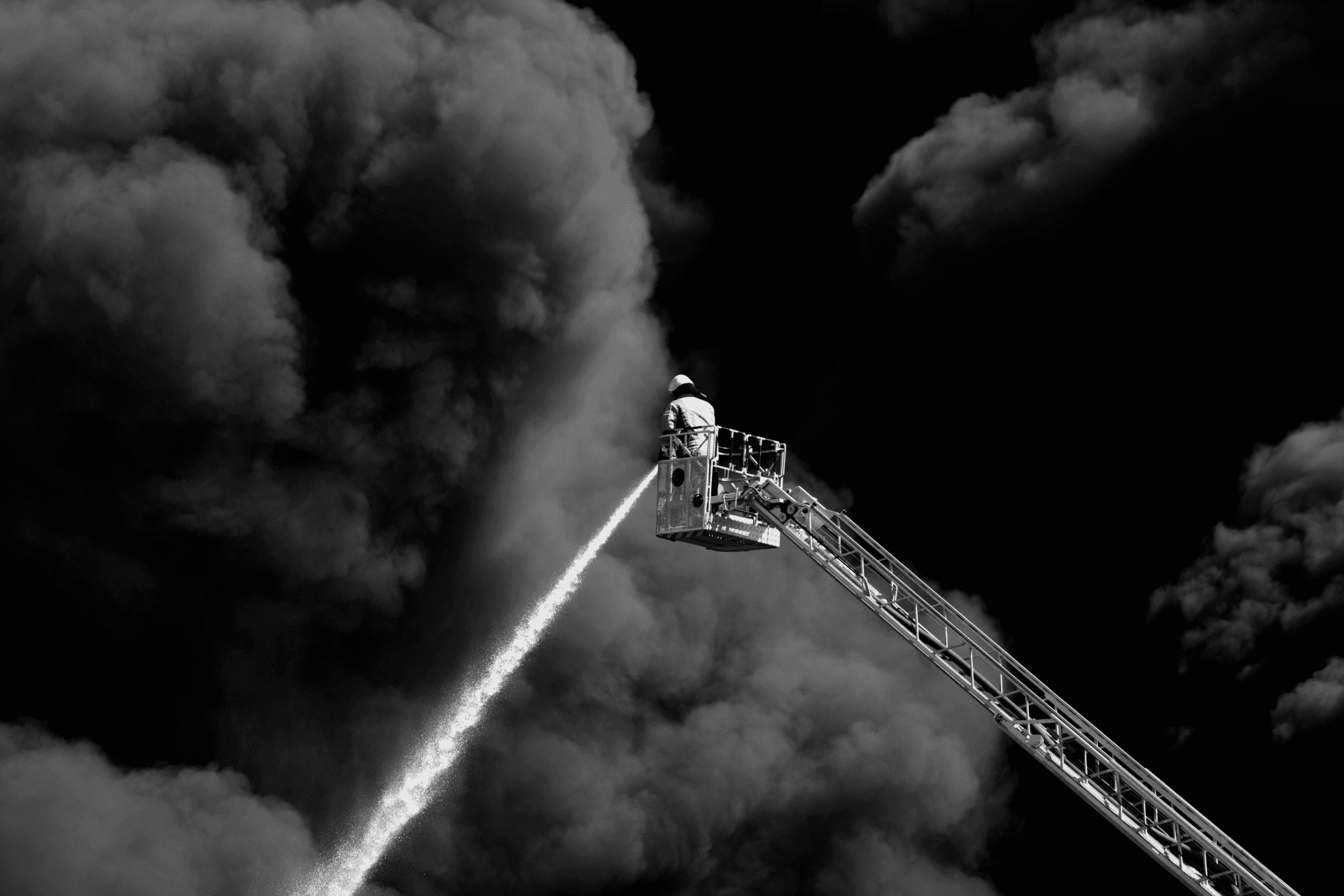 Firefighter on an aerial platform over a burning roof